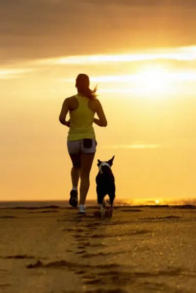 Woman Running with Dog at Sunrise