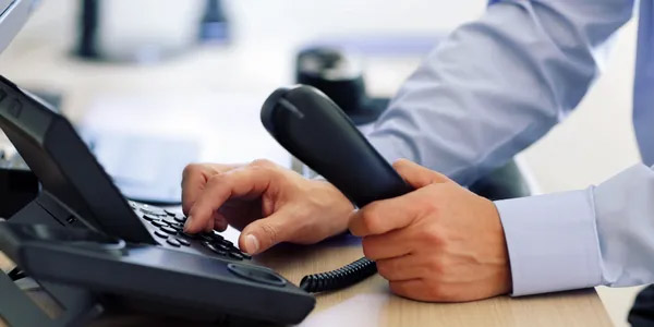 Man Dialing on Desk Phone